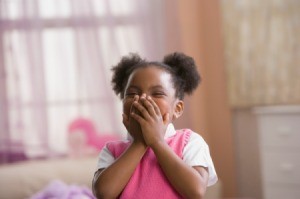 Cute little girl covering her mouth while laughing.