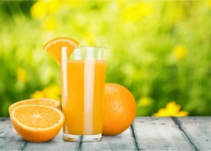 Glass of orange juice and a orange cut in half.