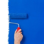 Paint roller painting a white wall blue.