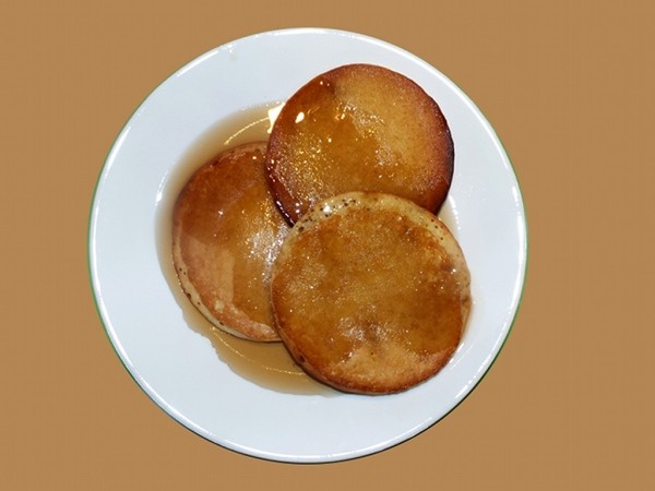 A plate of three pancakes with butter melted.