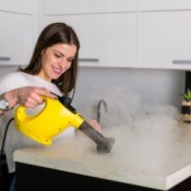 Woman using steamer to clean countertop