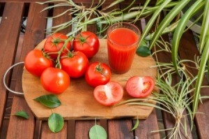 Tomatoes and tomato juice on wooden cutting board