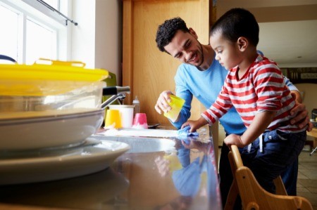 Father helping his son washing dishes