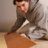 A man installing flooring on particle board.