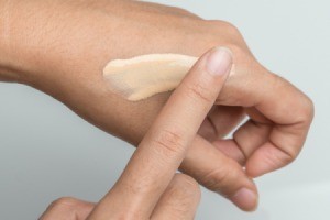A hand testing the tone of a tinted moisturizer.