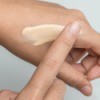 A hand testing the tone of a tinted moisturizer.