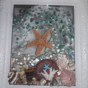 A frame with shells and glass to make a seascape.