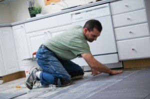 Man laying tile in a kitchen.