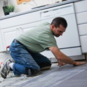 Man laying tile in a kitchen.