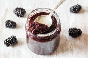 Blackberry Jam in jar with spoon and blackberries on wooden board