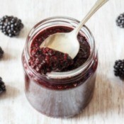 Blackberry Jam in jar with spoon and blackberries on wooden board