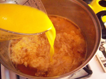 adding egg mixture slowly to simmering broth