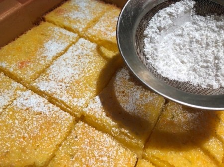 sprinkling powdered sugar on lime barsTangerine Lime Bars