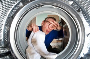 Man holding his nose putting smelly socks in the washing machine