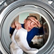 Man holding his nose putting smelly socks in the washing machine