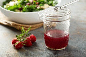 Raspberry Vinaigrette in mason jar with whisk, fresh raspberries and a salad