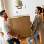 Couple carrying heavy box they have packed to move out