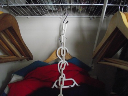 Clothes hanging from chains in the closet.