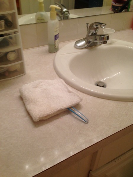 A toothbrush under a folded white washcloth.