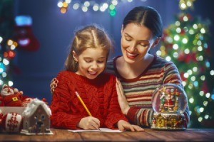 Mom and daughter writing a letter near the Christmas tree.