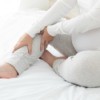 Pregnant woman with leg cramp sitting on bed