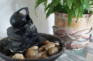 Tabletop fountain next to a plant.