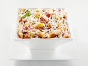 Pasta in a square bowl covered with parmesan.