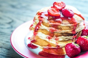 Stack of pancakes with strawberry syrup.