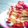 Stack of pancakes with strawberry syrup.