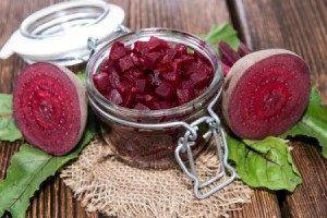 Pickled beets in a jar with a halved beet on the side