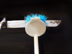 A scrub brush being used to clean a serrated knife.