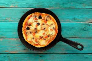 Pizza in a cast iron skillet on a painted wooden table