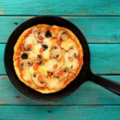 Pizza in a cast iron skillet on a painted wooden table