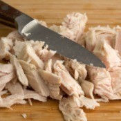 Leftover Turkey cut up into pieces on cutting board with knife