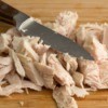 Leftover Turkey cut up into pieces on cutting board with knife