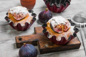 Fig muffins with fresh figs on the table next to them.