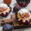 Fig muffins with fresh figs on the table next to them.