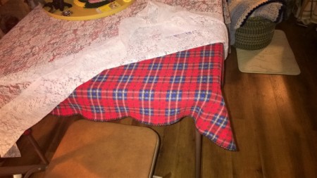A card table with a tablecloth over a puzzle in progress.