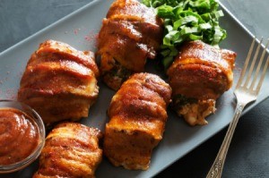 Bacon wrapped chicken on a grey plate.