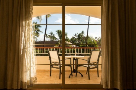 Looking through a sliding glass door to a balcony in a tropical place.