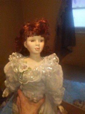 Identifying a Porcelain Doll - dark photo of a doll wearing a fancy dress with ruffled collar