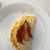An omelet on a plate with salsa on top.
