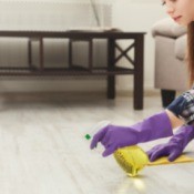 Woman wearing rubber gloves spraying the floor.
