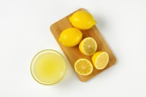 Cut lemons on a cutting board with lemon juice in a glass bowl