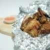 Baked chicken in aluminum foil on wooden cutting board