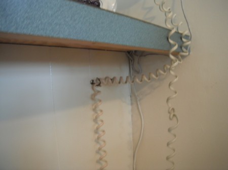 A long telephone cord hung on a hook under a counter.