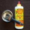 A bottle of Roach and Ant Killer containing boric acid, next to a paint brush dipped in boric acid powder.