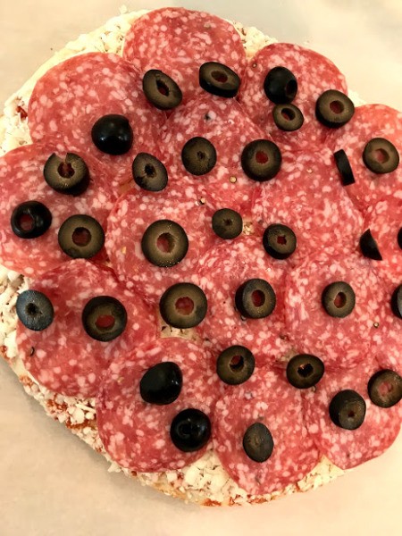 A pizza topped with salame and black olives.
