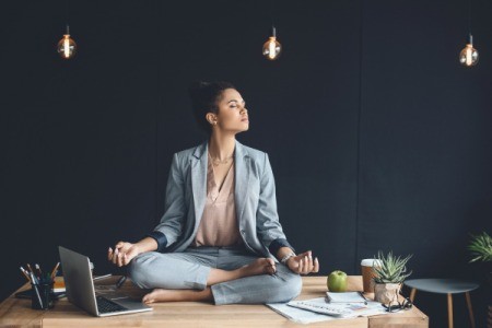 Woman meditating on her work desk.