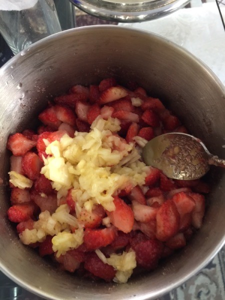 adding pineapple to strawberries in pot